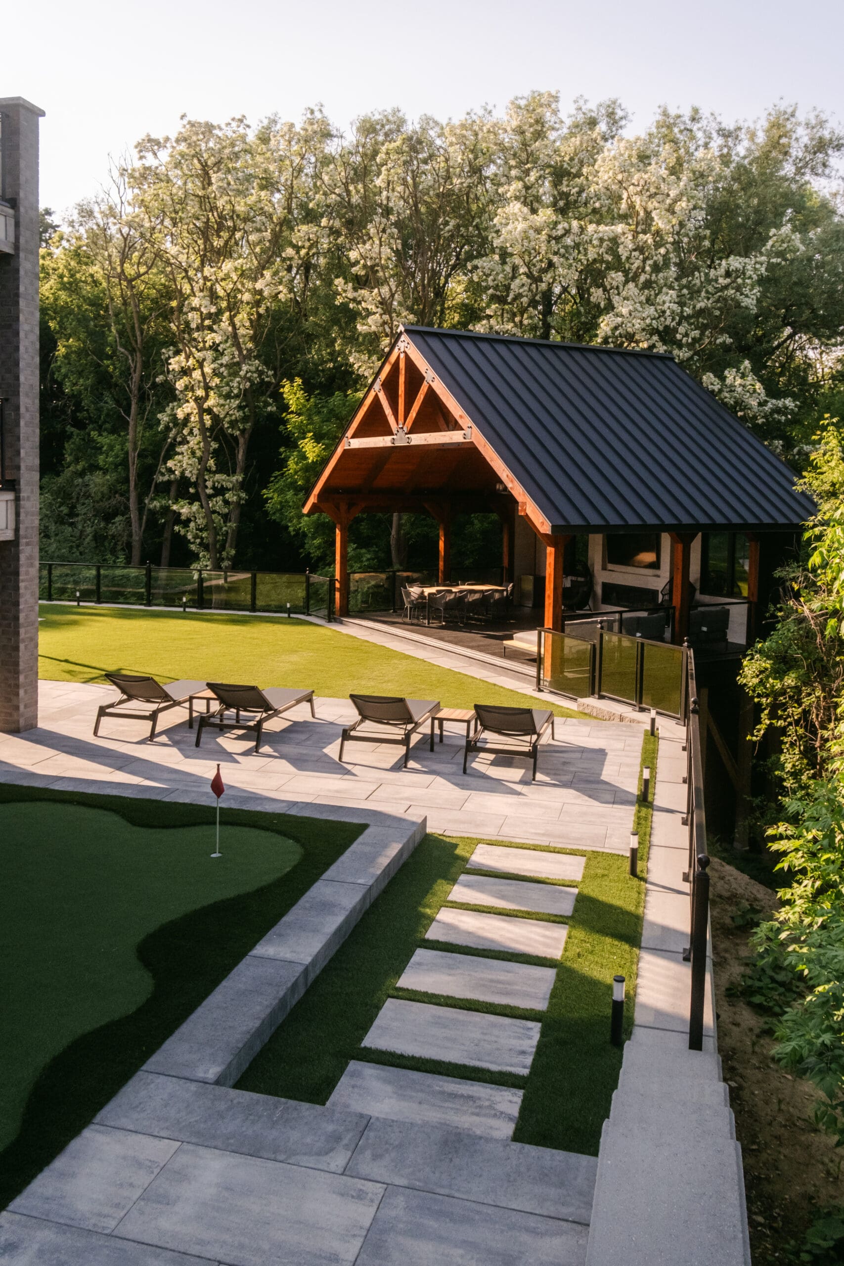 Custom timber gazebo with glass railing, interlock patio and putting green