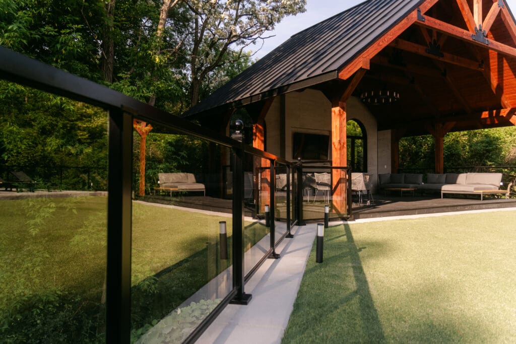 Gazebo with glass railings and lounge seating overlooking the backyard
