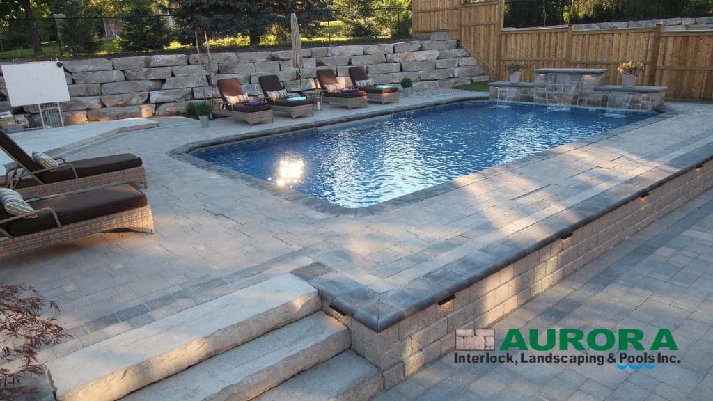 Stone retaining wall and pool coping on a sloped backyard